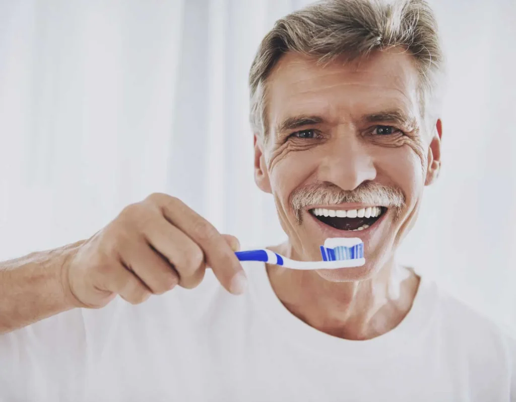 Senior man brushing teeth after dental cleaning at Beamsville Smiles Family Dentistry